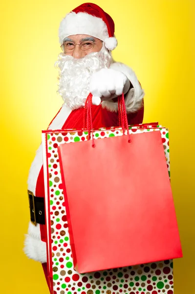 Cheerful Santa holding vibrant colored shopping bags — Stock Photo, Image