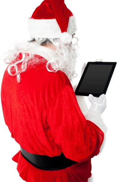 Achteraanzicht van santa kijken naar Tablet PC-apparaatscherm — Stockfoto