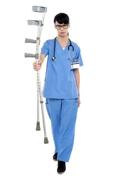 Sad doctor holding up crutches in hand — Stock Photo, Image