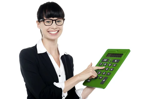 Bespectacled woman using big green calculator — Stock Photo, Image