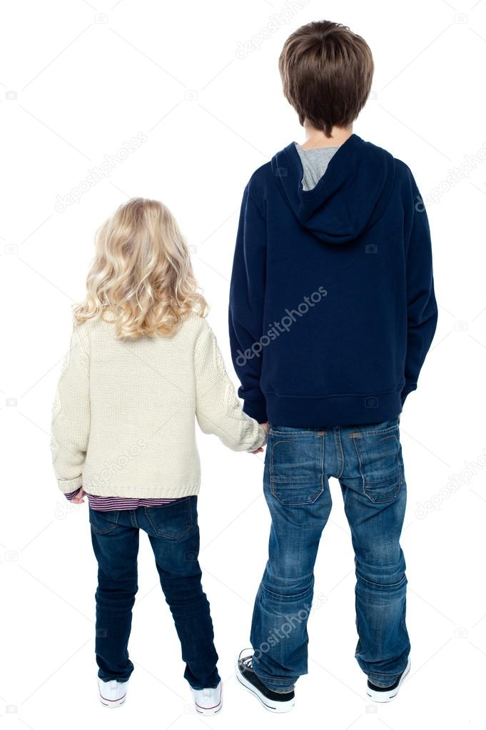 Rear view of two little kids. Boy holding his sister.