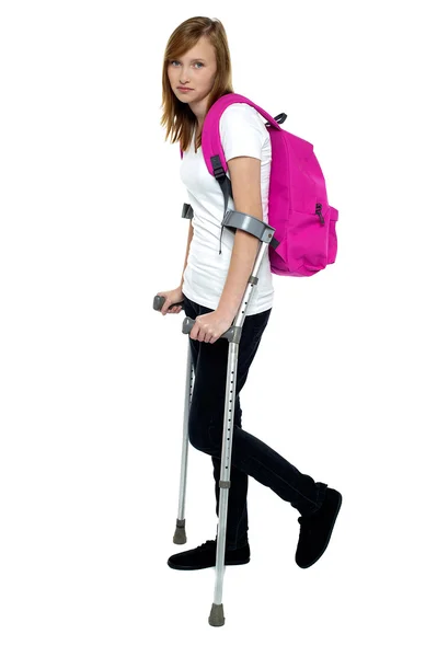 Teenager student holding crutches and walking — Stock Photo, Image