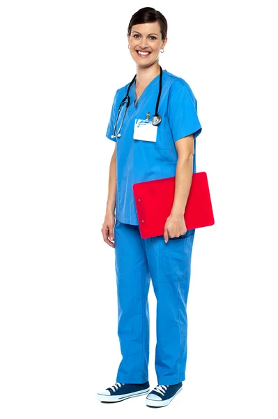 Enfermeira vestindo uniforme azul e segurando prancheta vermelha — Fotografia de Stock