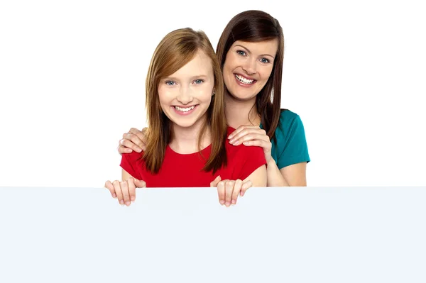 Girl holding ad board with her mother behind her — Stock Photo, Image