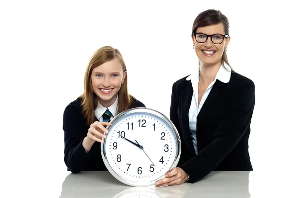 Pretty student holding clock with her teacher — Stock Photo, Image