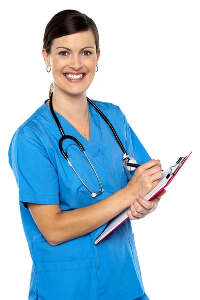 Smiling medical practitioner filling out the records Stock Image