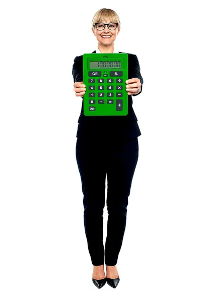 Femme en costume d'affaires affichant une grande calculatrice verte — Photo