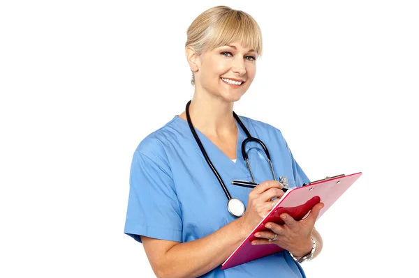 Médico con portapapeles sonriendo a la cámara — Foto de Stock