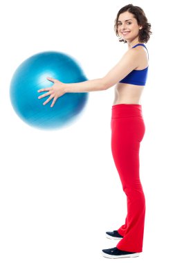 Fit woman posing with big blue exercising ball