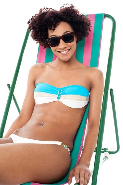 Sexy bikini model seated on a deckchair — Stock Photo, Image