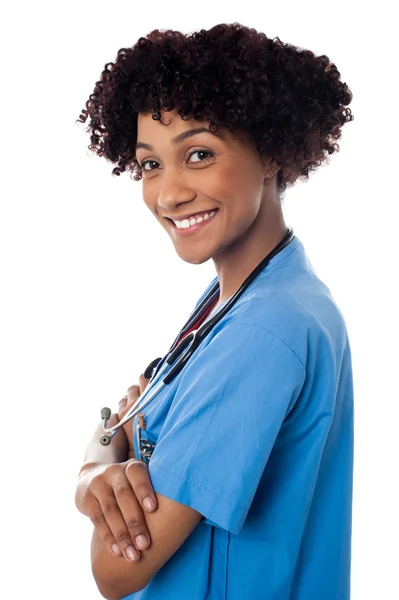 Médico sonriente de pie de lado con los brazos cruzados —  Fotos de Stock