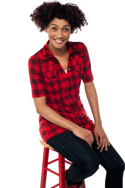 Curly haired fashion model sitting on red stool — Stock Photo, Image