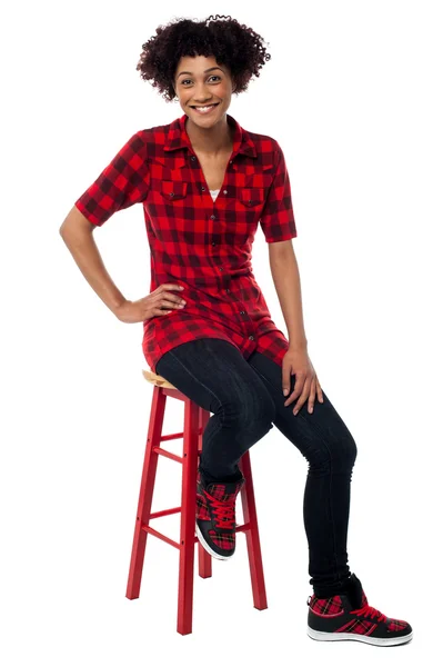 Casual young woman sitting on stool — Stockfoto