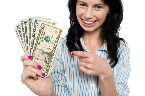 Mulher feliz segurando e apontando para notas de dólar — Fotografia de Stock