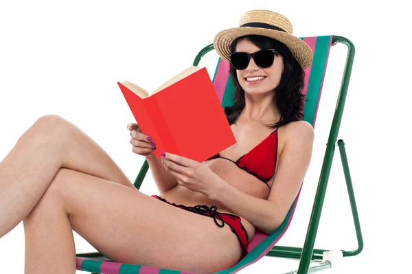 Enticing bikini model on a deckchair reading a book — Stock Photo, Image