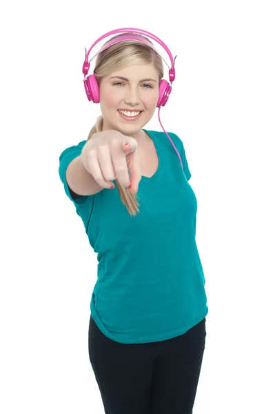 Young girl enjoying music and pointing at you — Stock Photo, Image