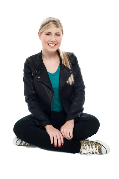 Cheerful teenager seated on floor, legs crossed — Stock Photo, Image