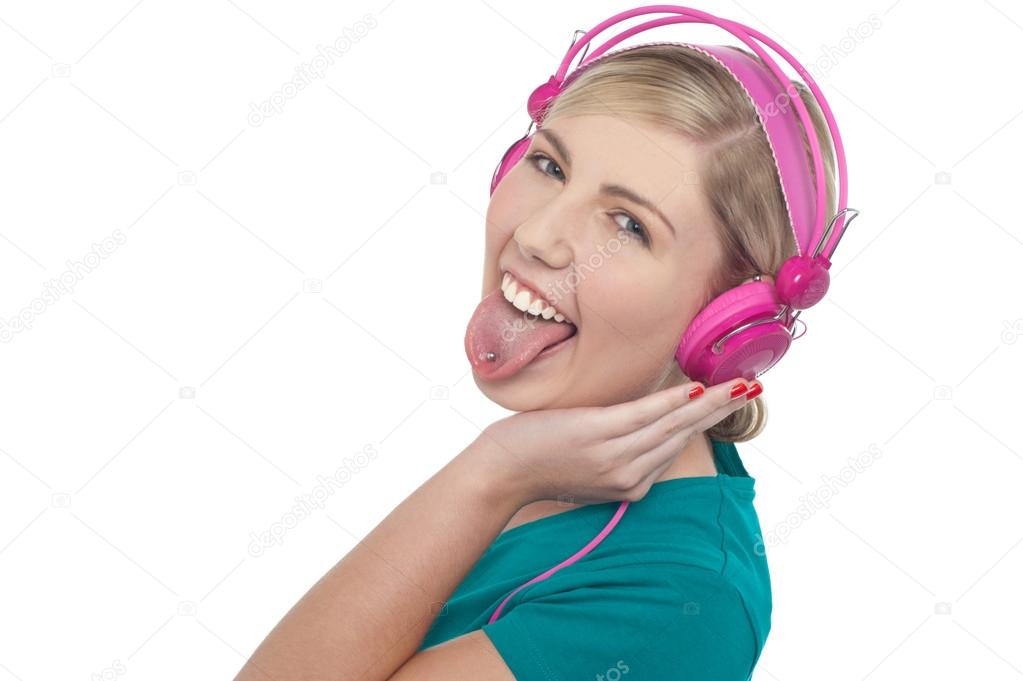 Woman with headphones on sticking her pierced tongue out