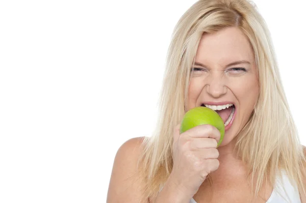 Närbild skott av en blond kvinna bita ett äpple — Stockfoto