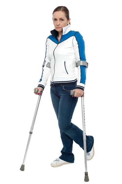 Femeie cu aspect pensiv folosind cârje pentru a merge pe jos — Fotografie, imagine de stoc