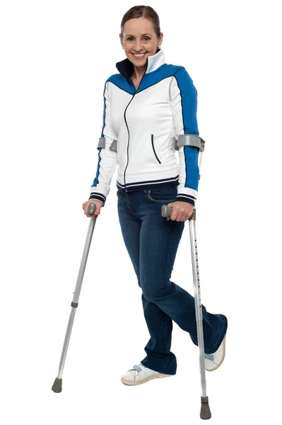 Kvinnan promenader med stöd av kryckor — Stockfoto