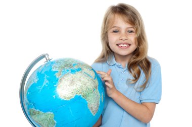 Pretty school child holding globe and pointing