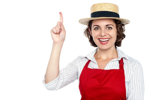 Усміхнена жінка в солом'яному капелюсі вказує геть — стокове фото