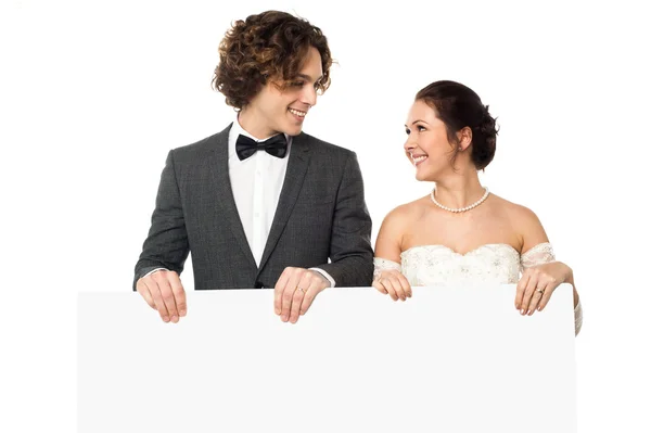 Pareja casada posando con un anuncio en blanco — Foto de Stock