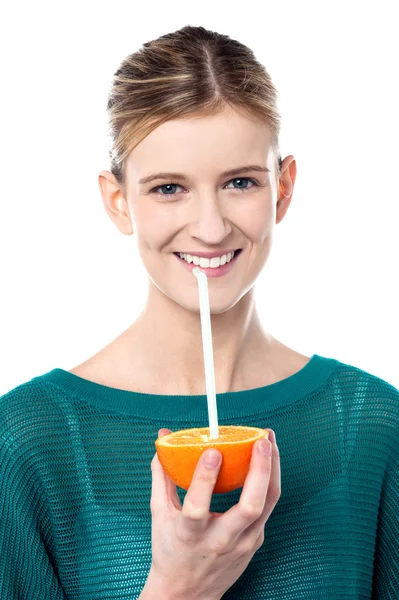 Девушка потягивает апельсиновый сок через соломинку — стоковое фото