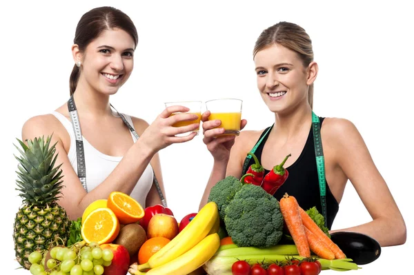 Young smiling girls each holding glass of juice — Stock Photo, Image