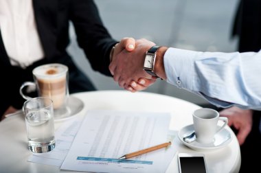 Business handshake over a coffee clipart