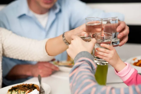 Family toasting water glasses in celebration — Stock Photo, Image