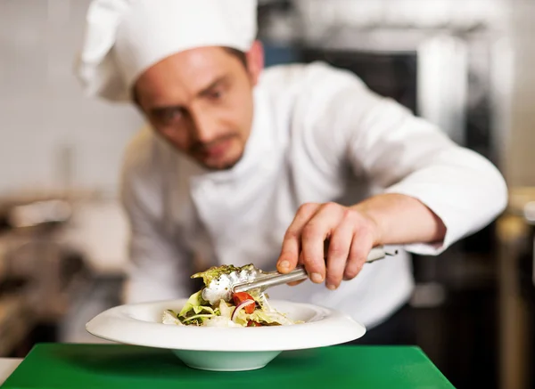 Un chef organisant une salade dans un bol blanc — Photo