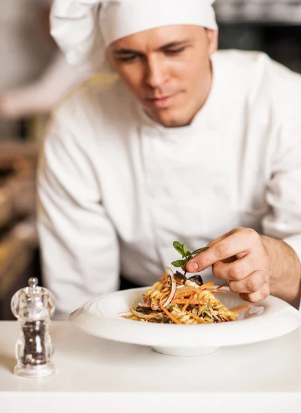 Chef-kok versieren pastasalade met kruiden verlaat — Stockfoto