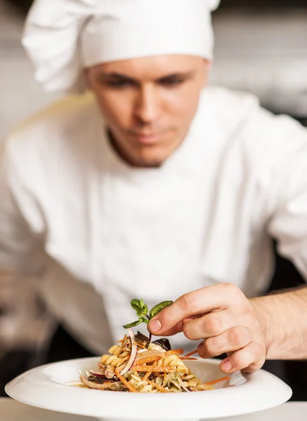 Chef decorando ensalada de pasta con hojas de hierbas — Foto de Stock