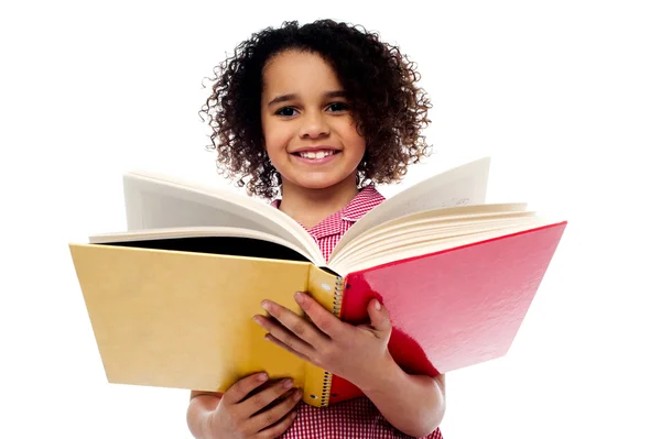 Adorável menina da escola lendo um livro com um sorriso — Fotografia de Stock