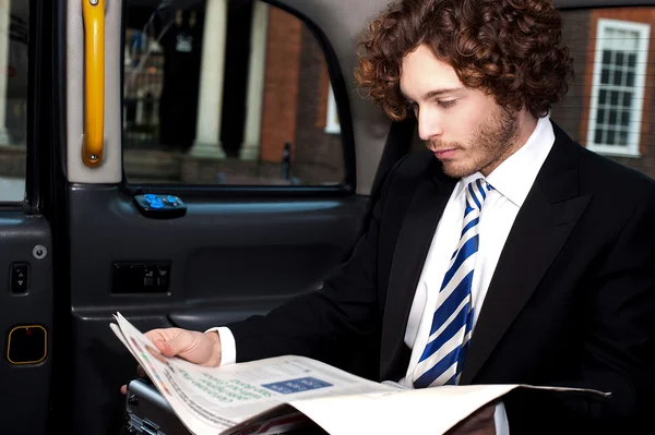 Zakenman lezing tijdschrift binnen taxi — Stockfoto
