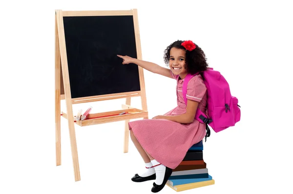 Cute smiling student pointing at blank chalkboard — Stock Photo, Image