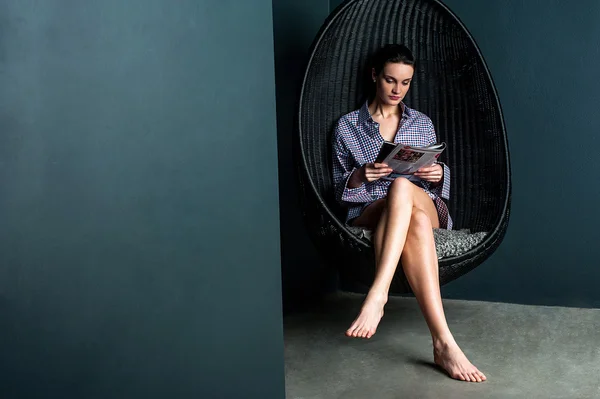 Женщина читает журнал, сидит на качающемся стуле — стоковое фото