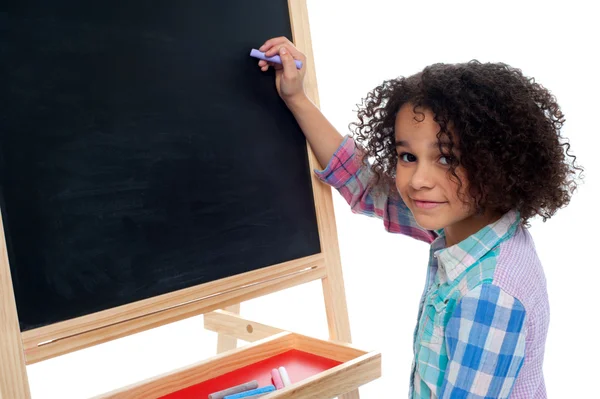 Schönes kleines Mädchen schreibt auf Klassenzimmertafel — Stockfoto