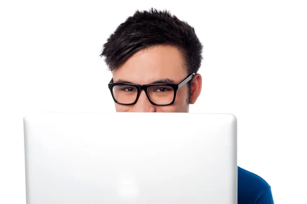 Chico travieso escondiendo su cara con el portátil —  Fotos de Stock