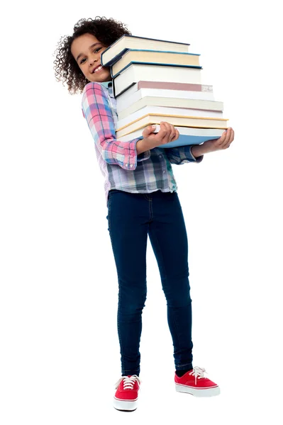 Criança alegre bonito que transporta pilha de livros — Fotografia de Stock