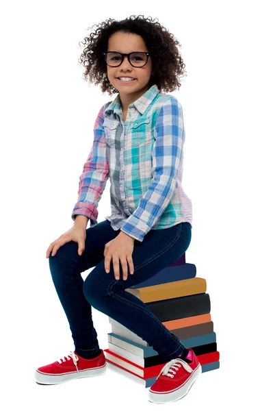 School girl sitting on stack of books — Stock Photo, Image