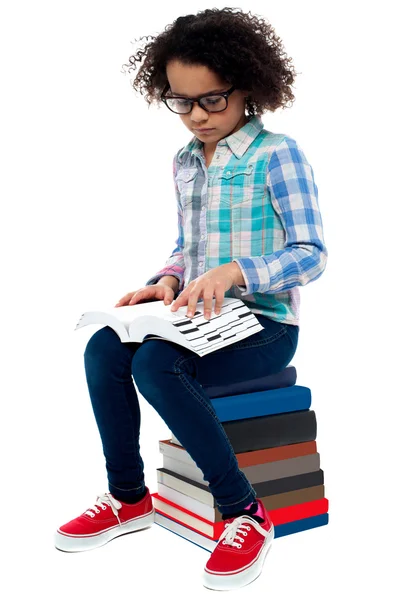 Jonge kind zittend op stapel boeken en lezen — Stockfoto