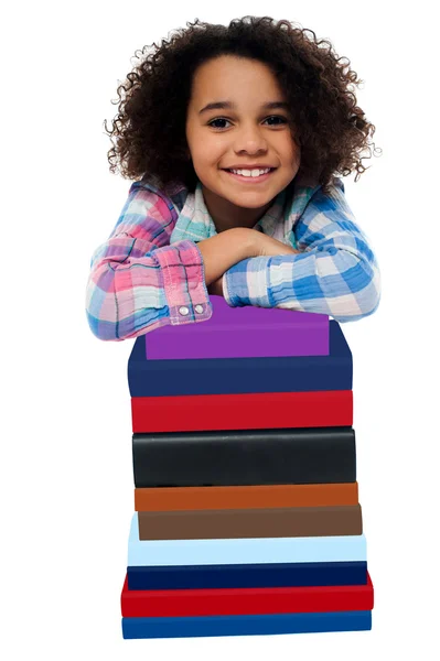Schickes kleines Mädchen lehnt sich über Bücherstapel — Stockfoto