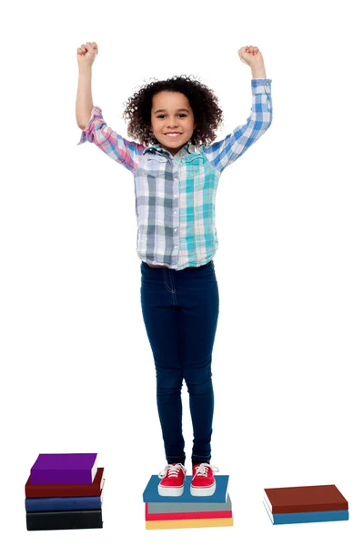 Excited pretty school child standing on books — Stock Photo, Image