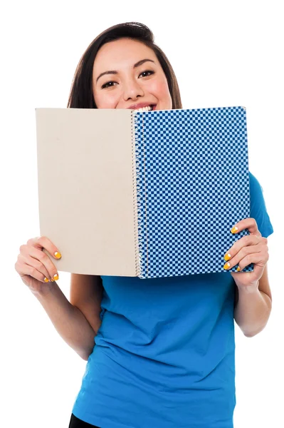 Junges Mädchen versteckt ihr Gesicht mit Notizbuch — Stockfoto