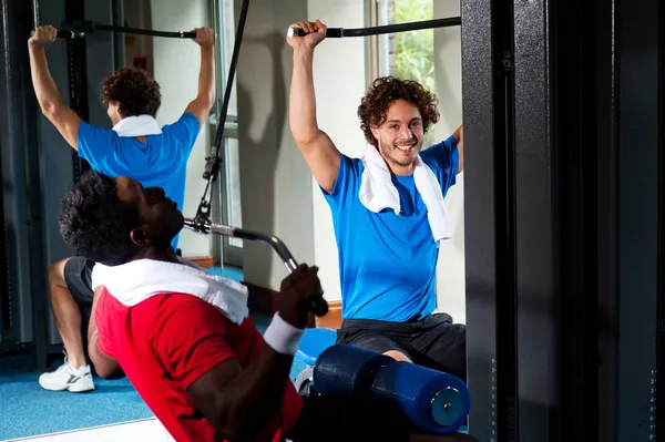 Strong young guys toning their upper body in gym — Stock Photo, Image