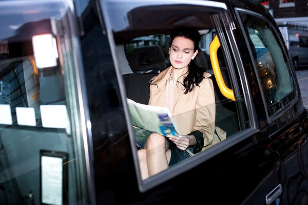 Passeggero donna che legge giornale dentro taxi — Foto Stock