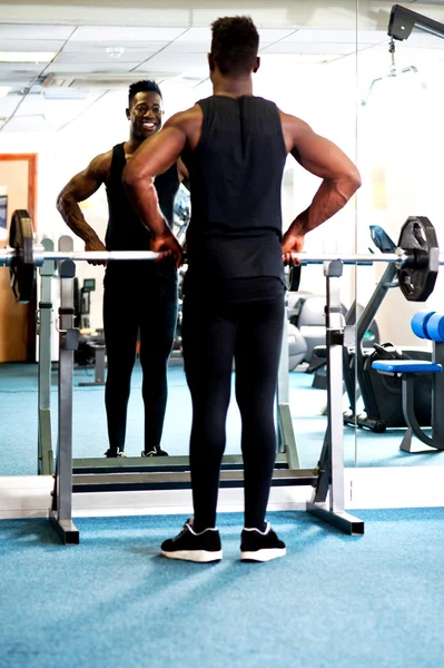 Молодой мускулистый парень смотрит на себя в зеркало — стоковое фото
